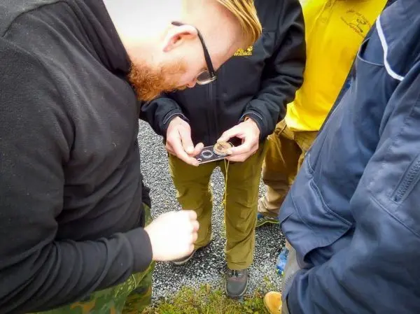 Eine Gruppe betrachtet gemeinsam eine Kompassnadel auf einem Tisch
