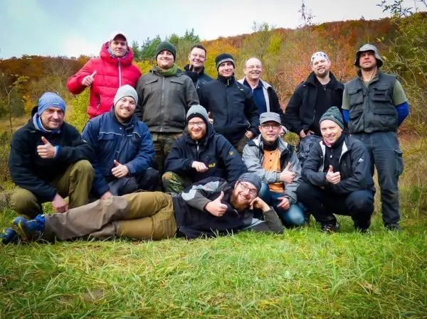 Gruppe von Männern posiert lächelnd im Freien auf einer Wiese