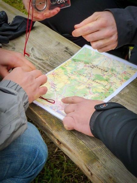Hände halten eine Karte und einen Kompass auf einem Tisch