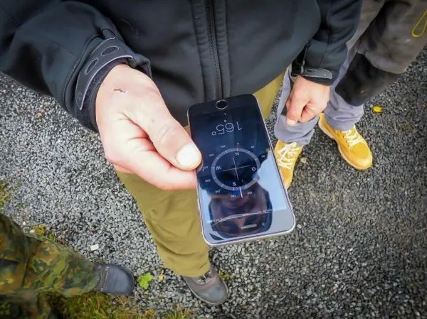 Hand hält Smartphone mit Kompass-App und Anzeige der Richtung