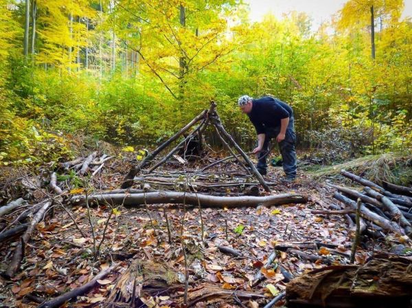 Holzkonstruktion wird mit Ästen für eine Notunterkunft aufgebaut