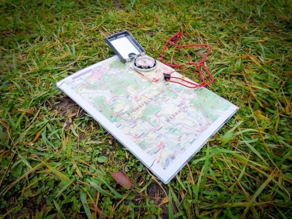 Karte und Kompass liegen auf grünem Gras
