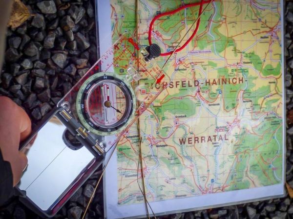 Kompass liegt auf einer topografischen Karte mit markierten Wegen