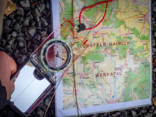 Kompass liegt auf einer topografischen Karte mit markierten Wegen