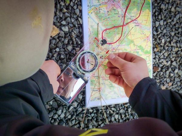 Kompass wird über eine Landkarte gehalten, um die Orientierung zu bestimmen