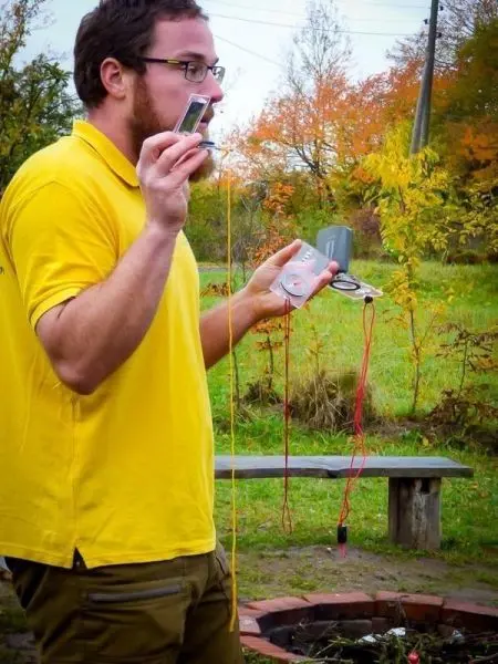 Mann hält zwei Kompasse und eine Schnur in der Hand, während er spricht