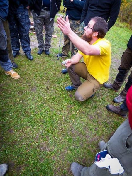 Mann in gelbem Shirt erklärt eine Technik im Freien, umgeben von Zuhörern