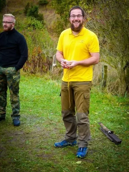 Mann mit gelbem Shirt hält Schnüre in der Hand, im Hintergrund steht ein anderer Mann