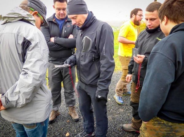 Mann mit GPS-Gerät erklärt Standortbestimmung an Gruppe von Teilnehmern