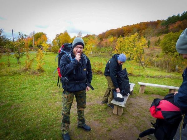 Mann mit Rucksack hält eine Wasserflasche, während ein anderer Rucksack packt