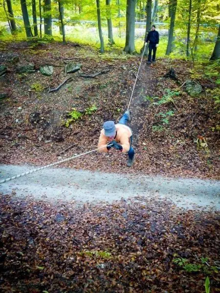 Mann nutzt Seil zur Abseilung an einem Hang im Wald