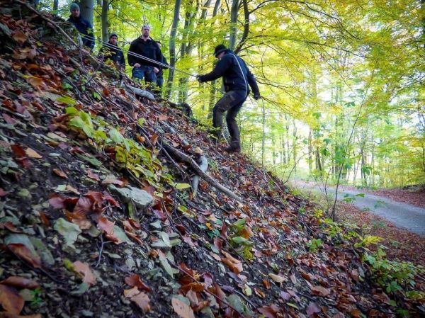 Mann nutzt Seil zur Abseilung an einem steilen Hang im Wald