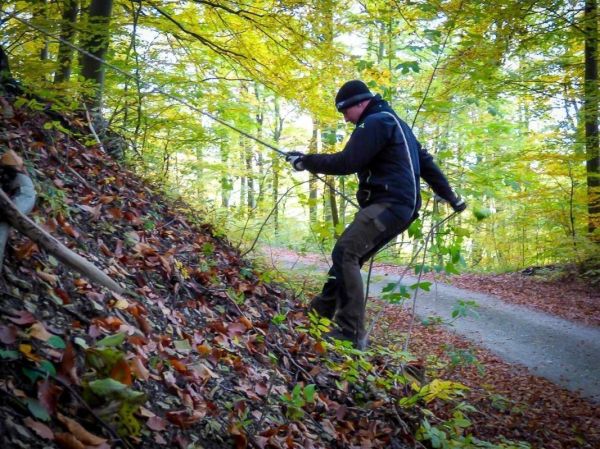 Mann nutzt Seil zur Unterstützung beim Abstieg an einem steilen Hang