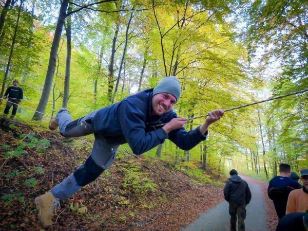 Mann schwingt an einem Seil zwischen Bäumen im Wald