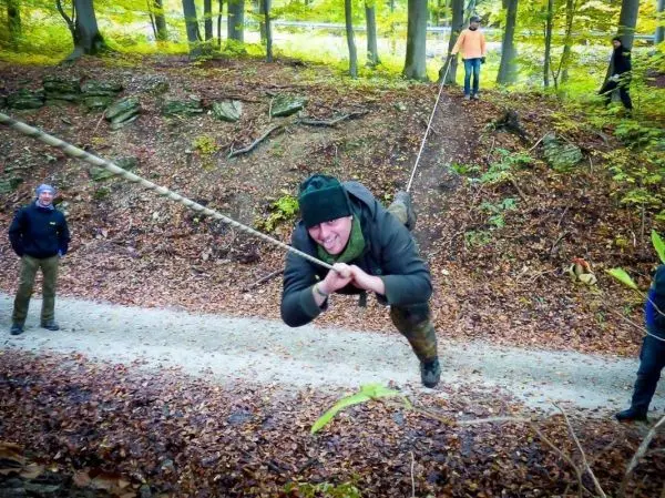 Mann schwingt an Seil über einen Hang im Wald