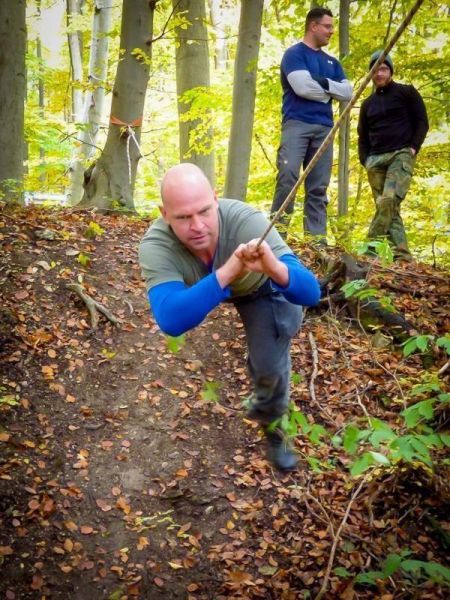 Mann zieht sich an einem Seil eine Steigung hinauf, während andere zuschauen