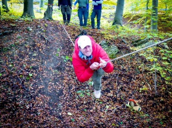 Mann zieht sich an einem Seil über einen steilen Hang im Wald