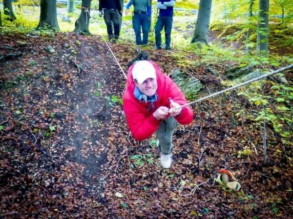 Mann zieht sich an einem Seil über einen steilen Hang im Wald