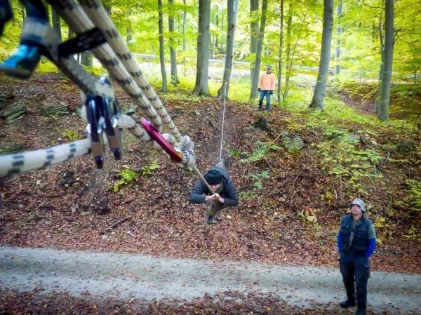 Person schwingt an Seil über den Boden im Wald beim Überlebenstraining