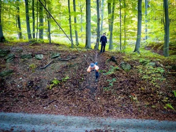 Person schwingt an Seil über einen Hang im Wald