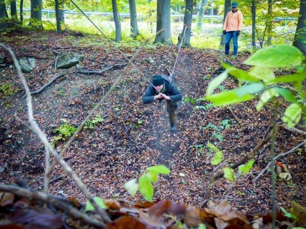 Person schwingt an Seil über einen Laubhang