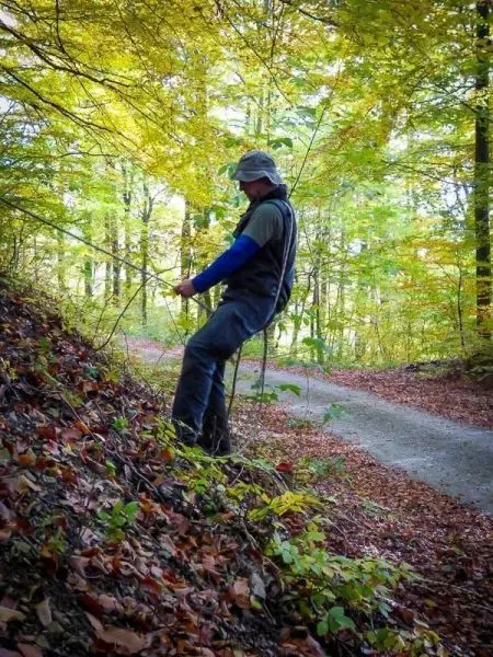 Person steht an einem Hang und hält ein Seil