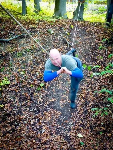 Person zieht sich an einem Seil entlang durch den Wald beim Überlebenstraining