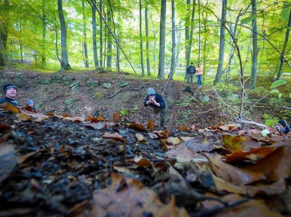 Seilbrücke über einen Graben mit Teilnehmern im Wald