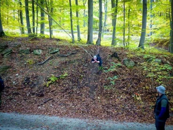Seilbrücke verbindet zwei Waldabschnitte, eine Person schwingt daran