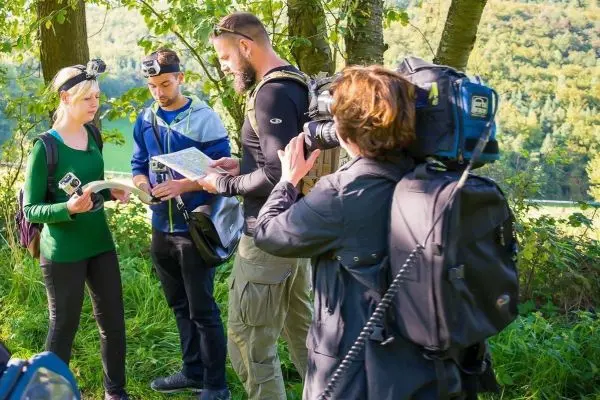 Drei Personen studieren eine Karte im Freien, während eine Kameraaufzeichnung erfolgt