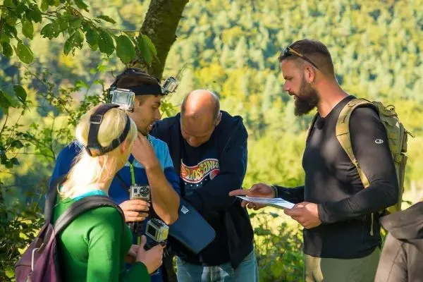 Gruppe betrachtet Kartenmaterial und Ausrüstung im Wald