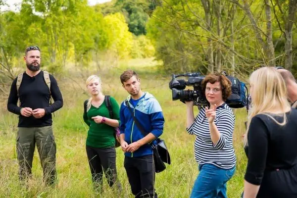 Gruppe diskutiert im Freien, eine Person hält eine Kamera