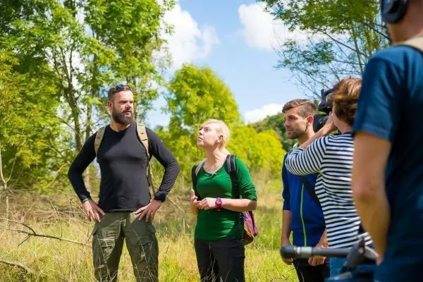 Gruppe diskutiert im Freien, während eine Person mit Kamera filmt