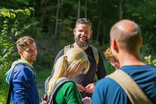 Gruppe von Personen steht in einem Wald und unterhält sich