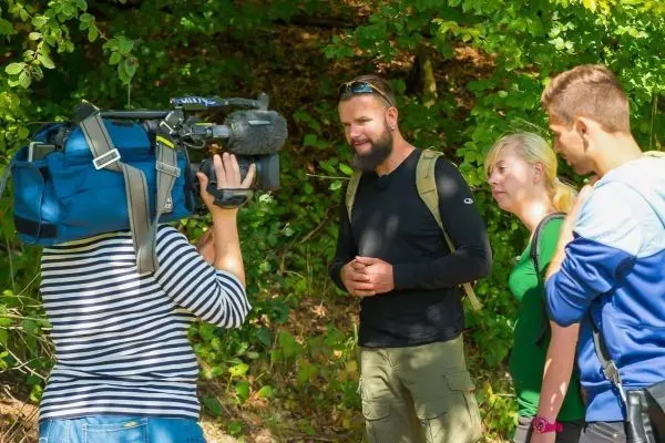 Kamera filmt Gespräch zwischen mehreren Personen im Wald