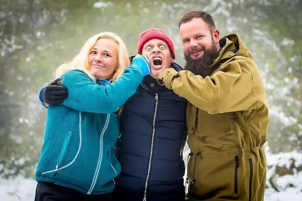 Drei Personen posieren in winterlicher Umgebung, lachen und machen Grimassen
