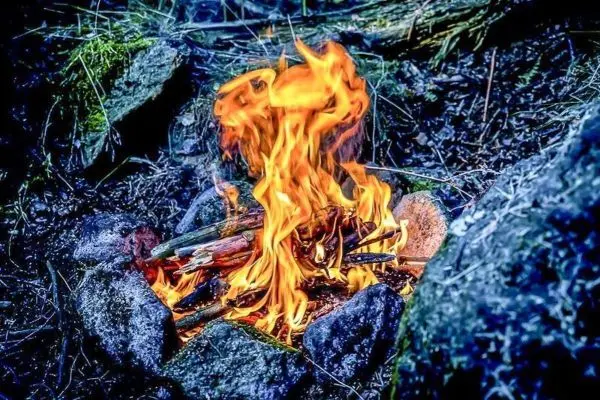 Kleine Flamme in einem Steinkreis mit Holzstücken