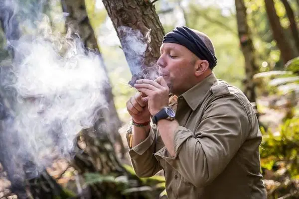 Kleines Bodenfeuer raucht, während Zunder angezündet wird