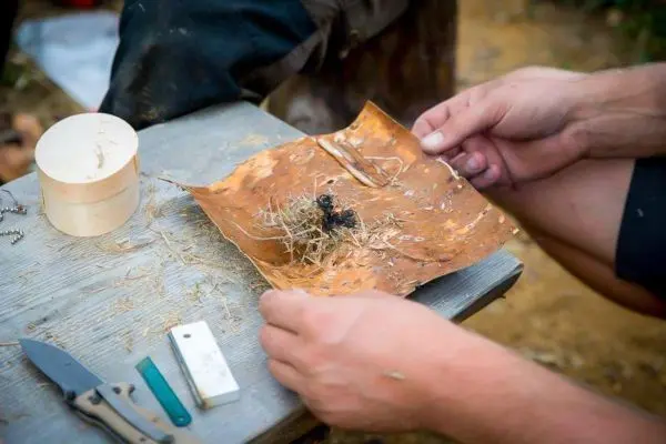 Zunder liegt auf einem Blatt, Hände halten es bereit zum Zundern