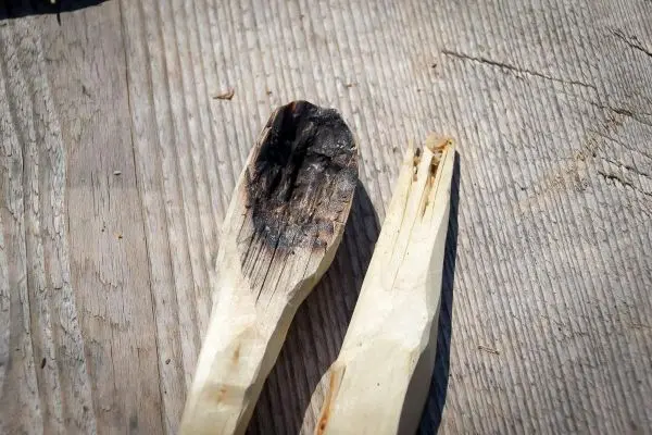 Zwei selbstgefertigte Holzlöffel mit Brandspuren und Rissen auf einer Holzoberfläche
