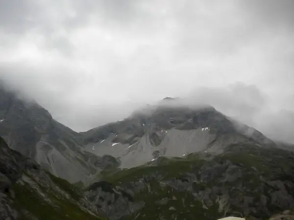 Berglandschaft mit bewölktem Himmel und Nebel über den Gipfeln
