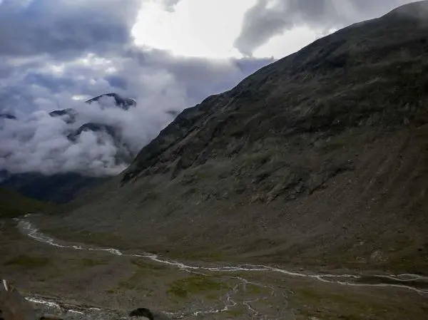 Berglandschaft mit steilen Hängen und einem kleinen Fluss im Tal
