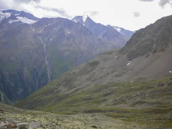 Berglandschaft mit steilen Hängen und schneebedeckten Gipfeln im Hintergrund