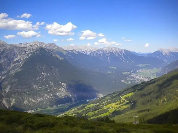 Berglandschaft mit Tälern, Fluss und bewaldeten Hängen unter blauem Himmel