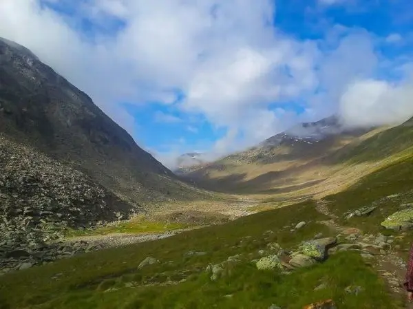 Bergtal mit steilen Hängen, Wiese und schmalem Pfad im Vordergrund