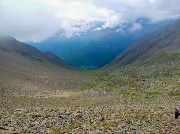 Blick ins Tal mit steiniger Landschaft und einem blauen See im Hintergrund