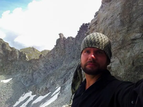Felsige Berglandschaft mit schneebedeckten Stellen und wolkigem Himmel im Hintergrund