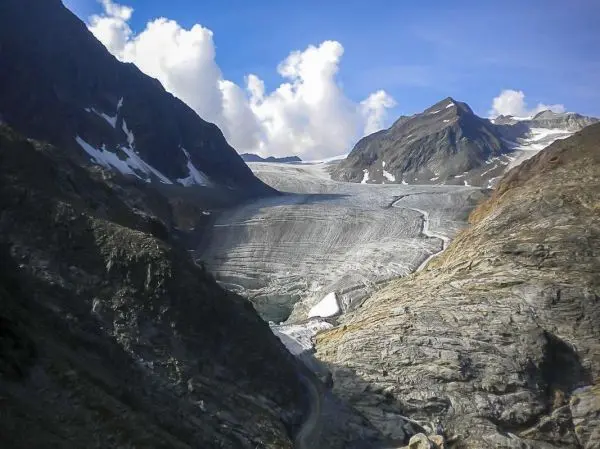 Gletscher zwischen steilen Felswänden und schneebedeckten Gipfeln in den Alpen
