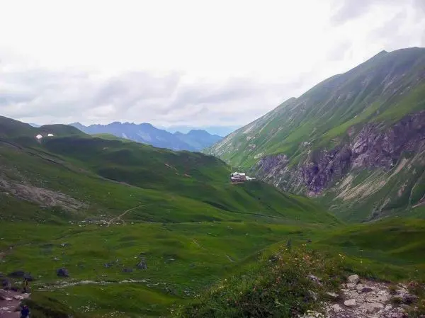 Grüne Berglandschaft mit sanften Hügeln und einem Gebäude im Tal