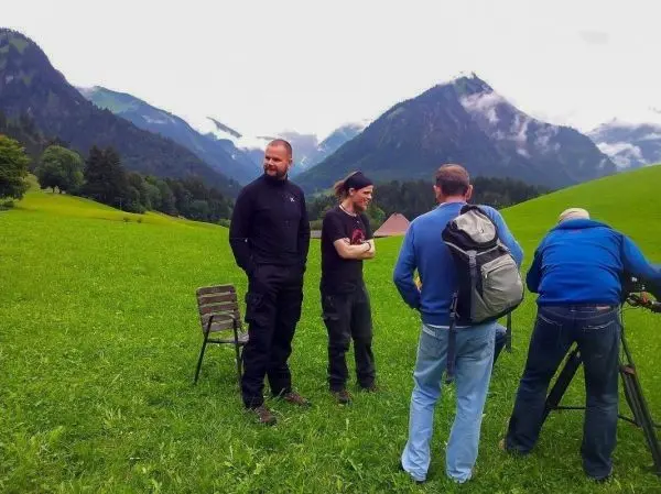 Gruppe von Personen auf einer Wiese mit Stuhl und Kameraausrüstung im Hintergrund